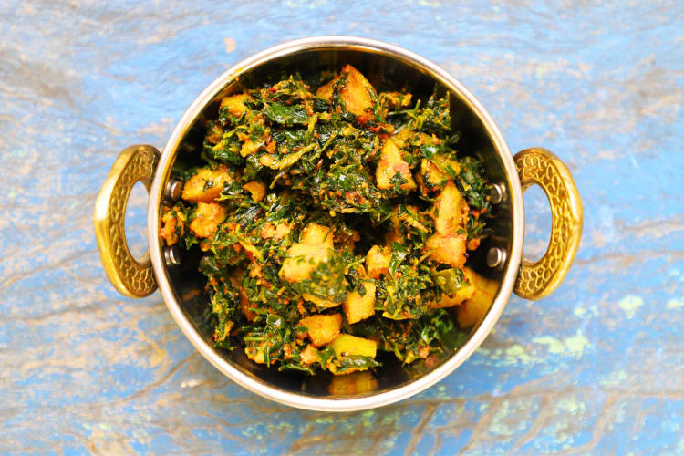 A bowl of saag aloo, a North Indian dish of fried potatoes with onions and tomatoes. 
