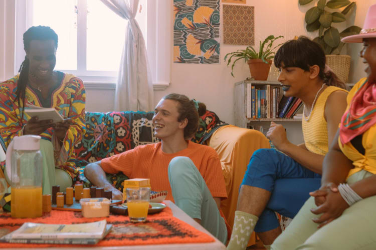 a group of people sit in a living room laughing and chatting together