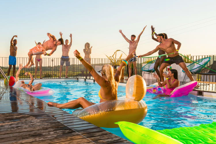 People in and jumping into a swimming pool