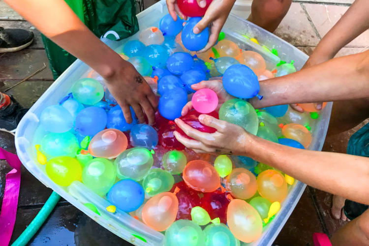 Kids taking colorful water balloons from a bucket