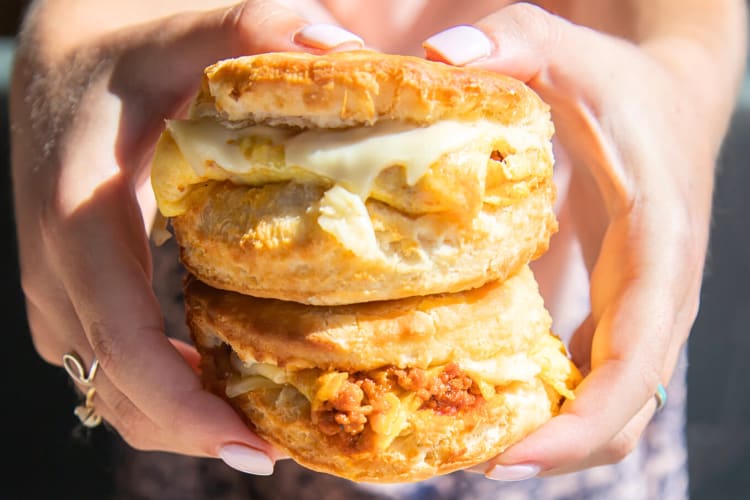 Person's hands holding two Carl's Jr. breakfast biscuits