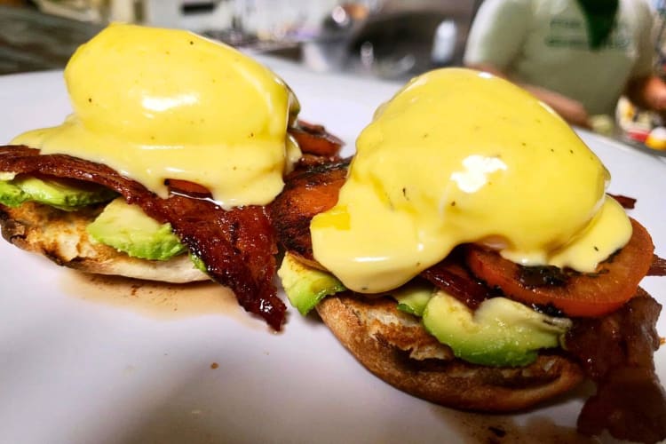 Eggs benedict meal with avocado, bacon and grilled tomatoes from Baja Café