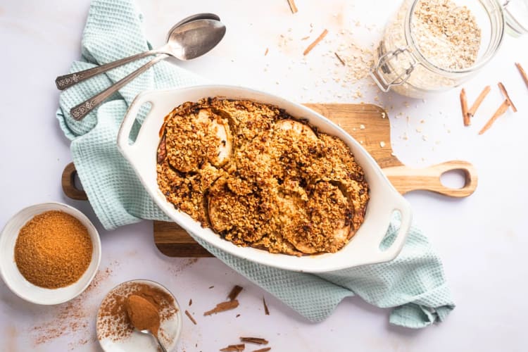 Aerial view of baked apple oatmeal in a dish, surrounded by oats and spices