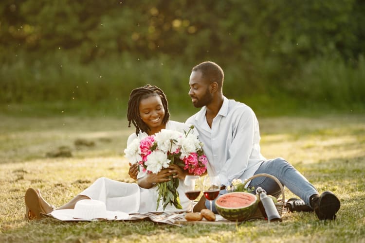 A couple sitting on the grass having a picnic