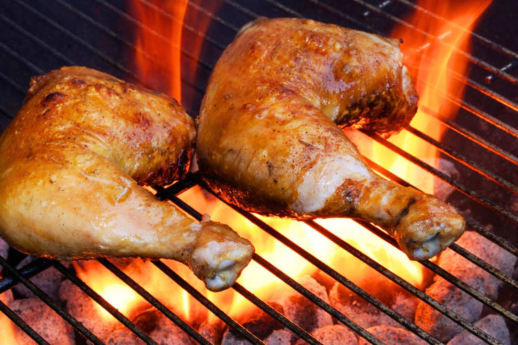 Two barbecue airline chicken cuts being grilled on a fire