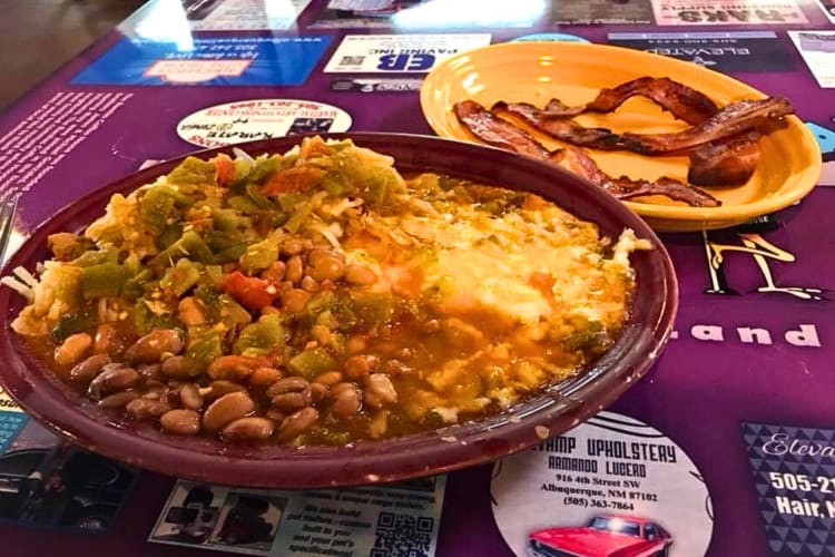Breakfast meal with eggs, chile, beans and cheese, and bacon on a separate plate