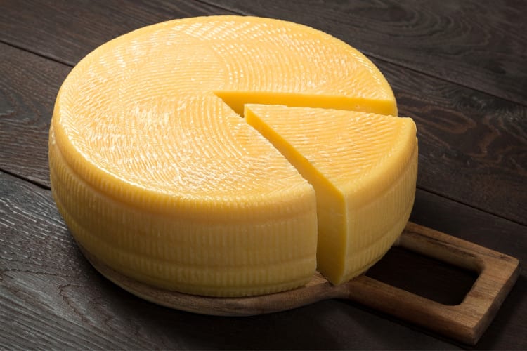 A wheel of cheese with a slice partially taken out