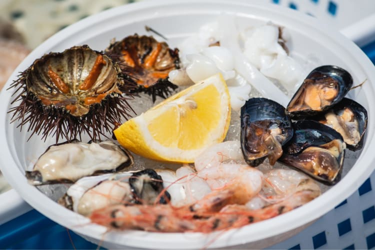 Different types of raw seafood and lemon on a plate
