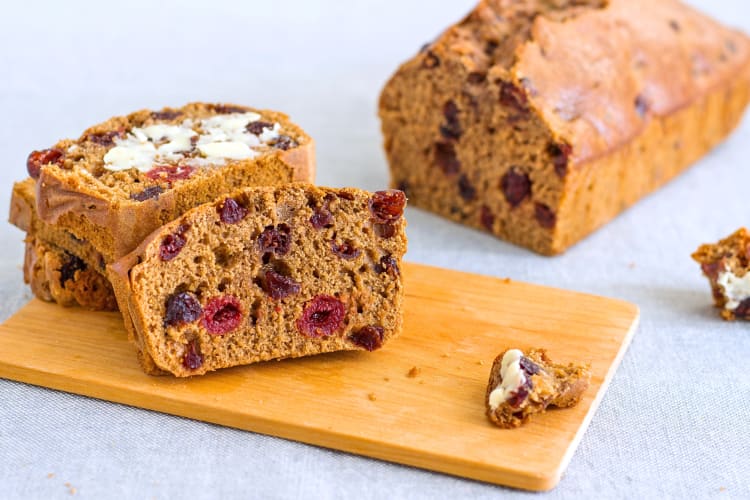 Barmbrack slices on a chopping board with the rest of the loaf behind it