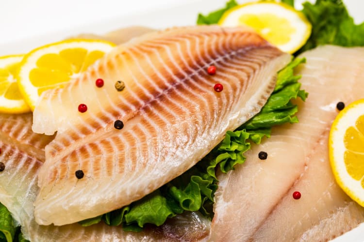 Filets of fish with salad leaves and lemon slices.