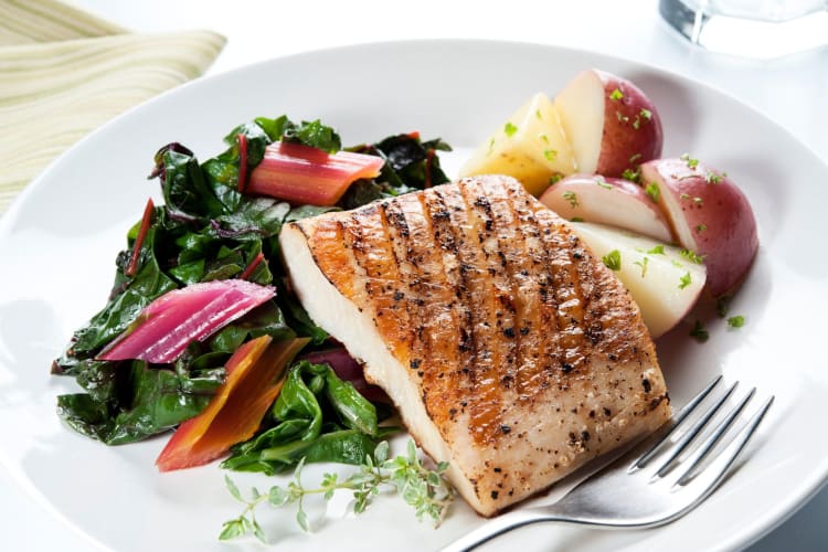 A filet of white fish served with a healthy salad.