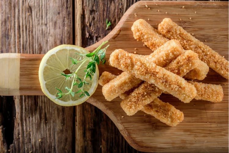 Breaded fish strips served with lemon and a herb garnish.