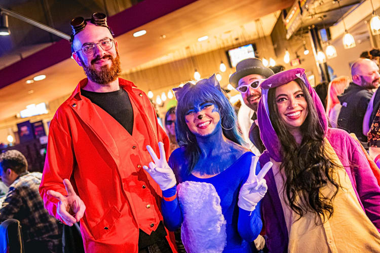 Three people dressed up as different characters posing for a picture during a party at Battle & Brew