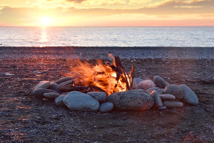 Beach bonfire with a sunset in the background