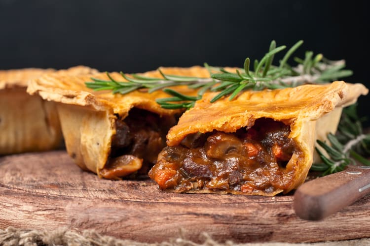 Beef and Guinness pie cut in half with green garnish leaf on top