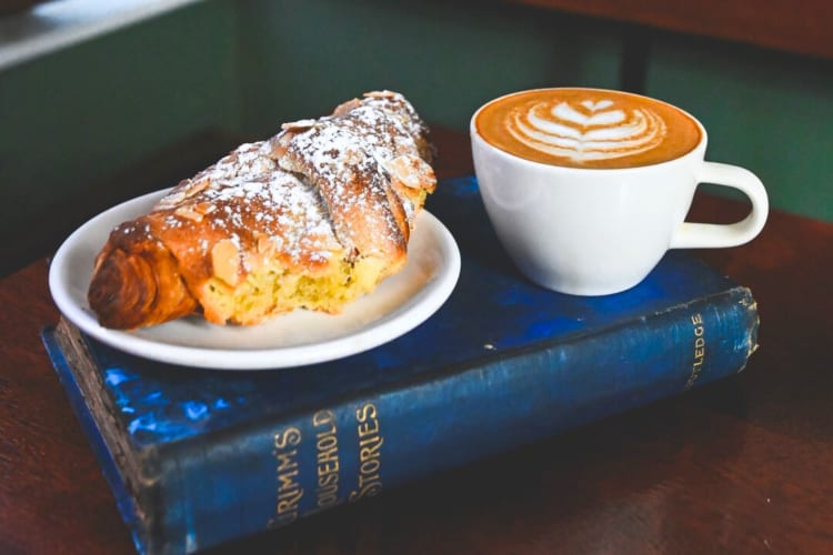 A croissant and a cup of coffee on top of a book