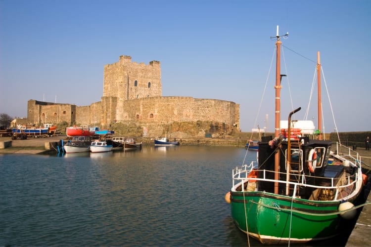 A castle next to the water and a green boat
