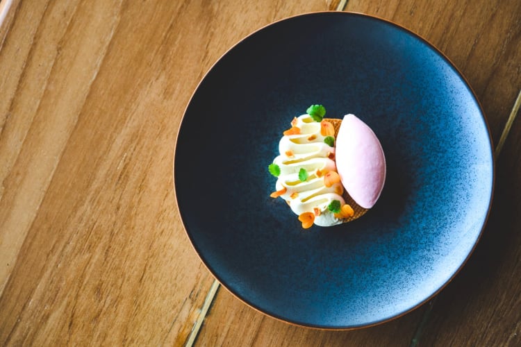 A high-end dessert with edible flowers on a blue plate