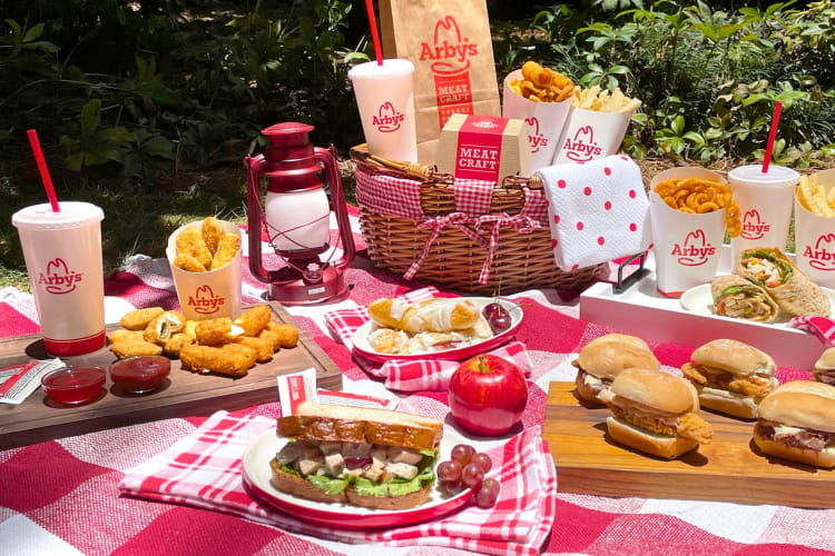 A selection of dishes from Arby's on a red and white picnic blanket 