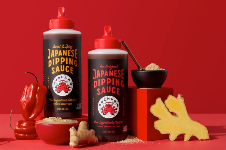 Two bottles of barbecue sauce next to fresh ginger and hot peppers