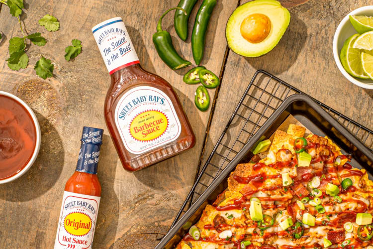 A bottle of Sweet Baby Ray's BBQ sauce next to nachos