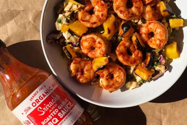 A bottle of Sriracha barbecue sauce next to a shrimp salad