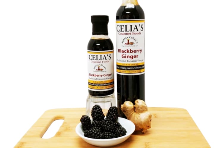 Two bottle of balsamic vinegar next to fresh blackberries and ginger
