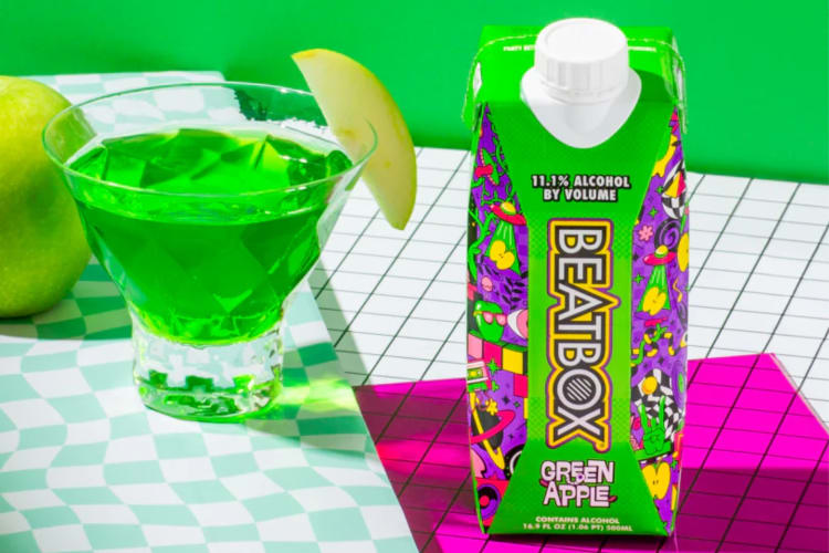 A Green Apple flavored BeatBox drink next to a glass with a green beverage