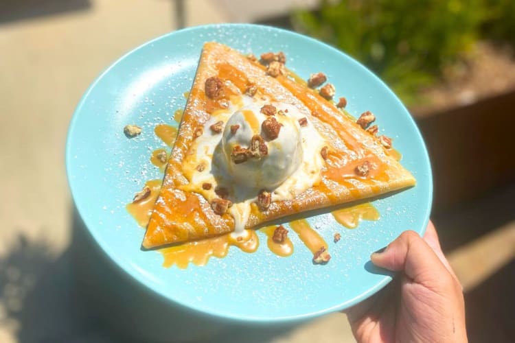 A crepe on a blue plate with ice cream and caramel