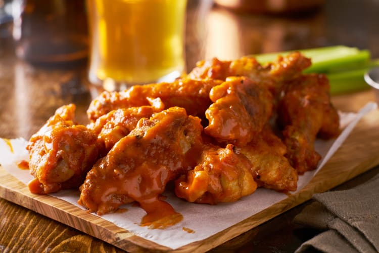 Wings coated in Buffalo sauce on a board
