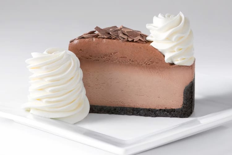 A slice of chocolate mousse cheesecake next to whipped cream