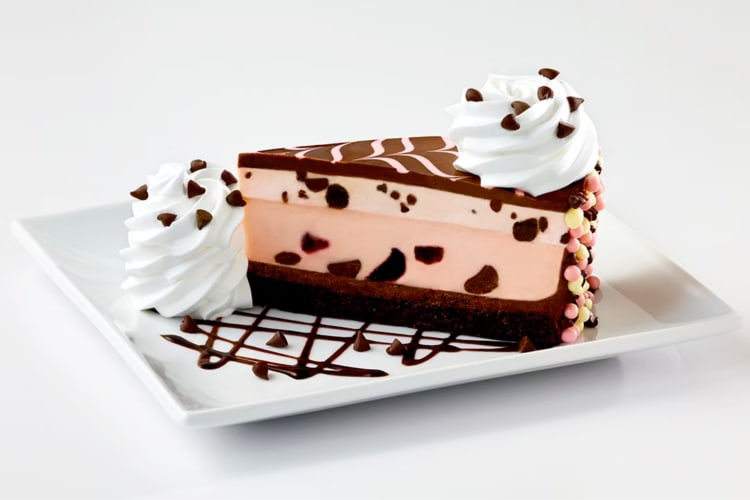A slice of chocolate cherry cheesecake with whipped cream