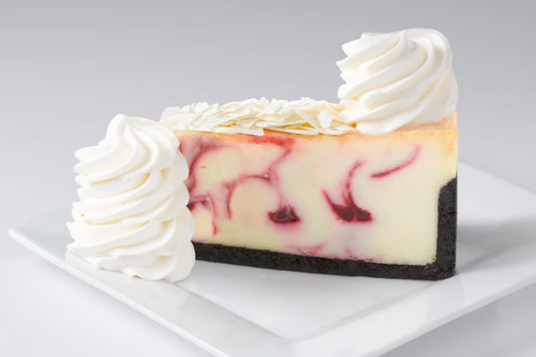 A white chocolate and raspberry cheesecake slice with whipped cream