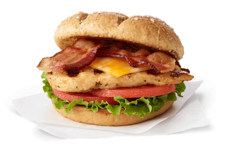 A sandwich with grilled chicken, bacon, cheese, lettuce and tomato