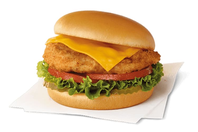 A chicken sandwich with breaded chicken, cheese, lettuce, pickles and tomatoes