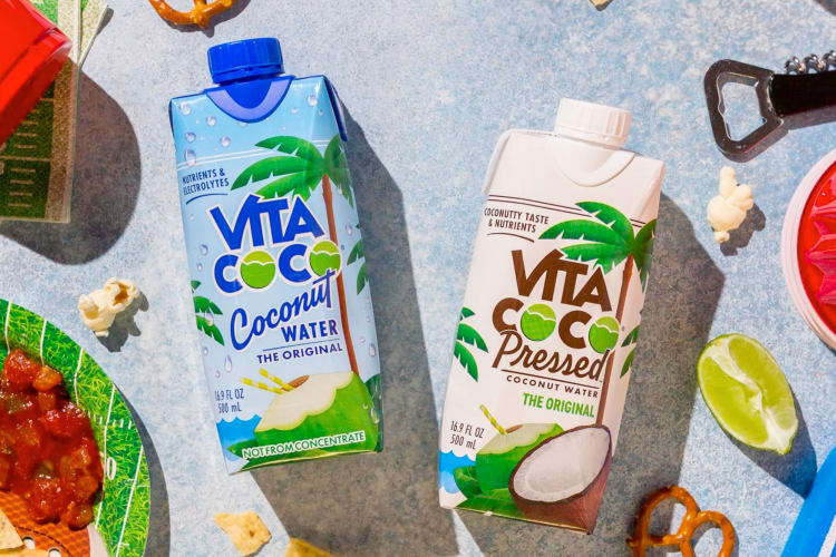 Two coconut water containers surrounded by snacks