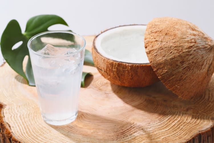 A fresh coconut next to a glass of coconut water