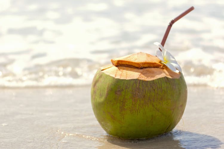 A young coconut drink with a straw on the beach