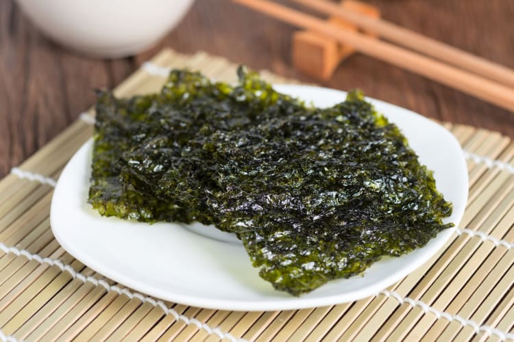 Dried seaweed sheets on a plate on a sushi rolling mat