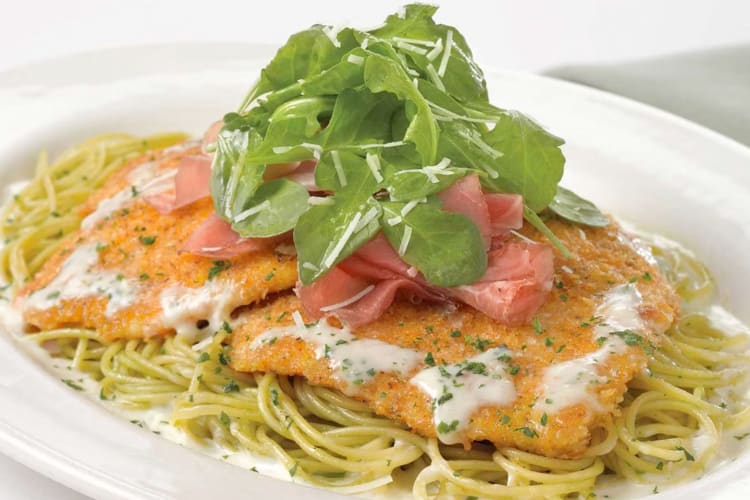 Of dish of spaghetti topped with breaded chicken, arugula and prosciutto