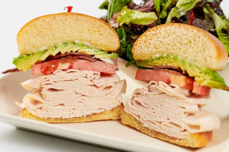 A turkey sandwich with lettuce, tomato and avocado