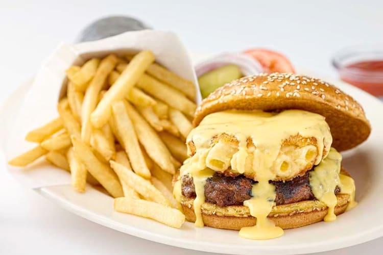 A burger with macaroni and cheese next to fries