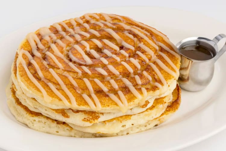 A plate of cinnamon roll pancakes with syrup