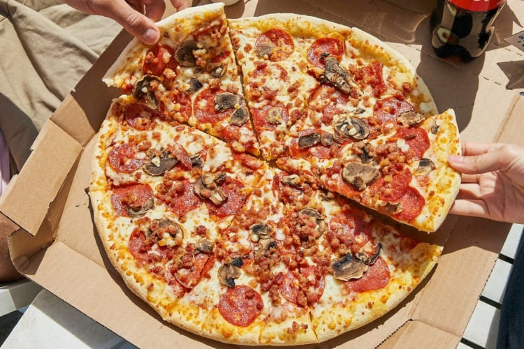 A pizza with mushrooms and multiple types of meats