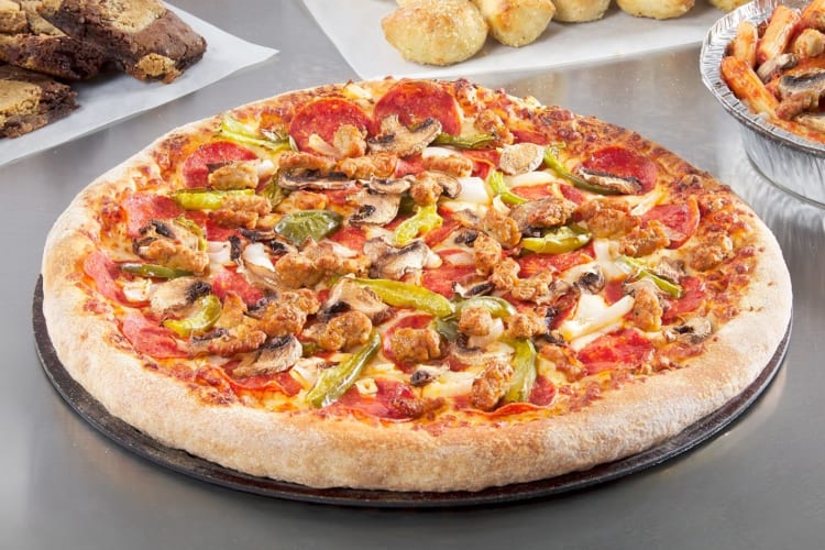 A pizza from Domino's with meat and vegetable toppings