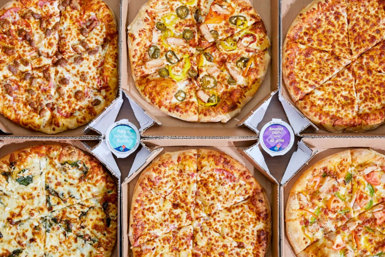 Six different pizzas from Domino's in takeout boxes