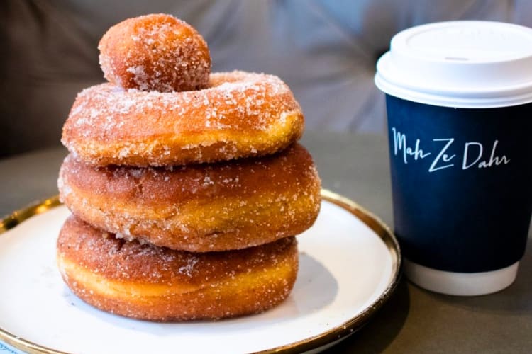 A donut next to a blue take-out coffee cup