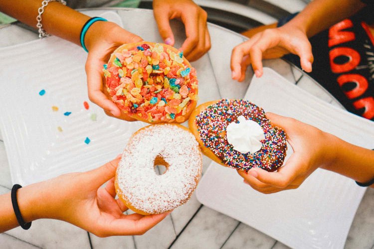 Three people holding donuts