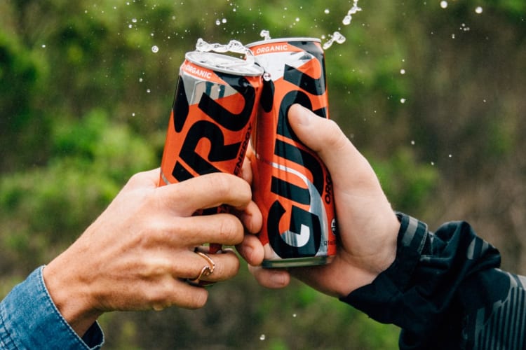Two people cheersing Guru energy drinks