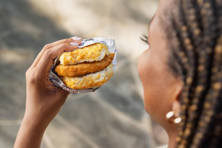 A lady enjoying a Chicken Biscuit from Chick-fil-A.